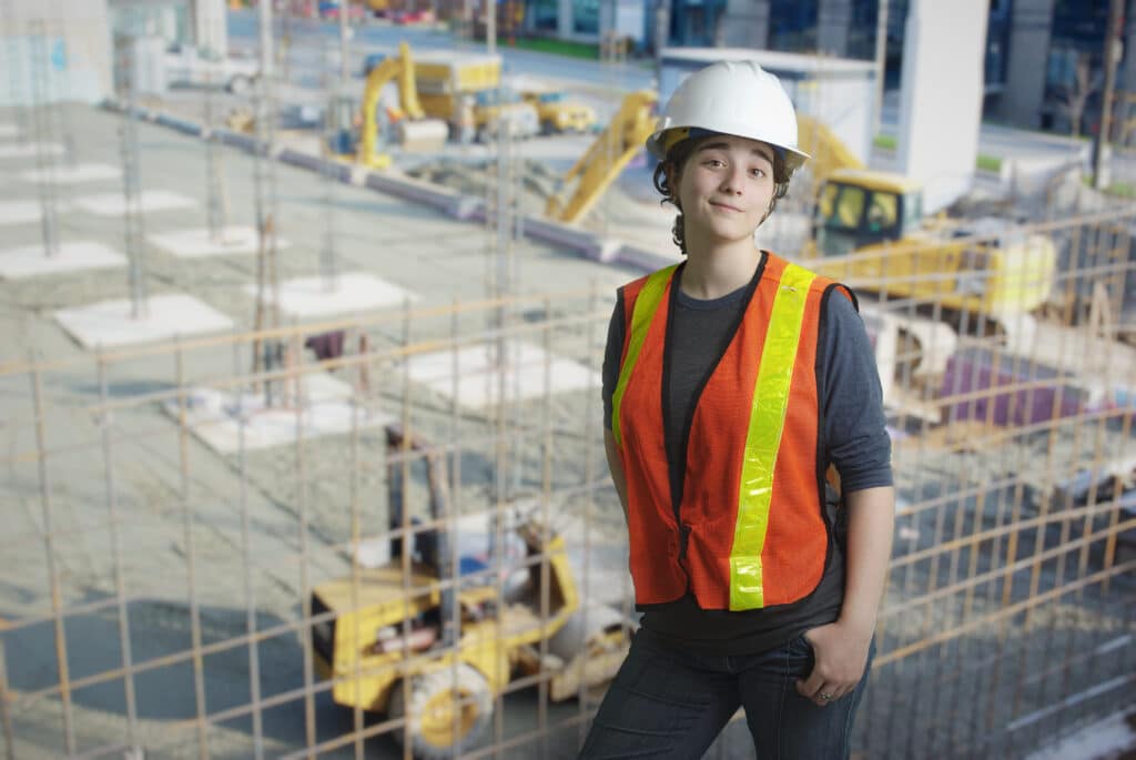 young woman on construction site working white hat job success