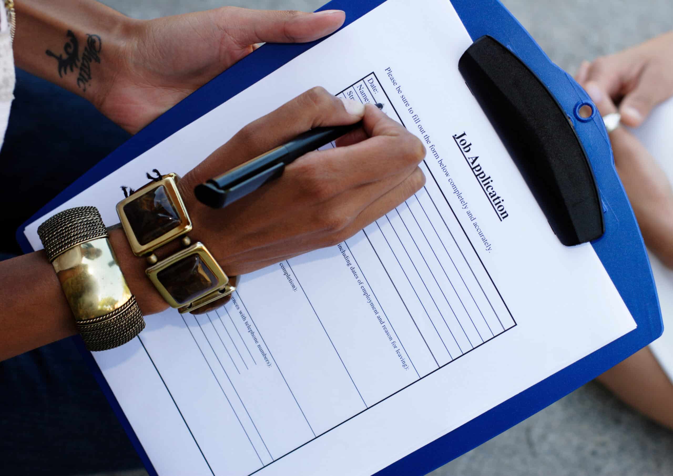 close up of a woman's hand filling out a job application.