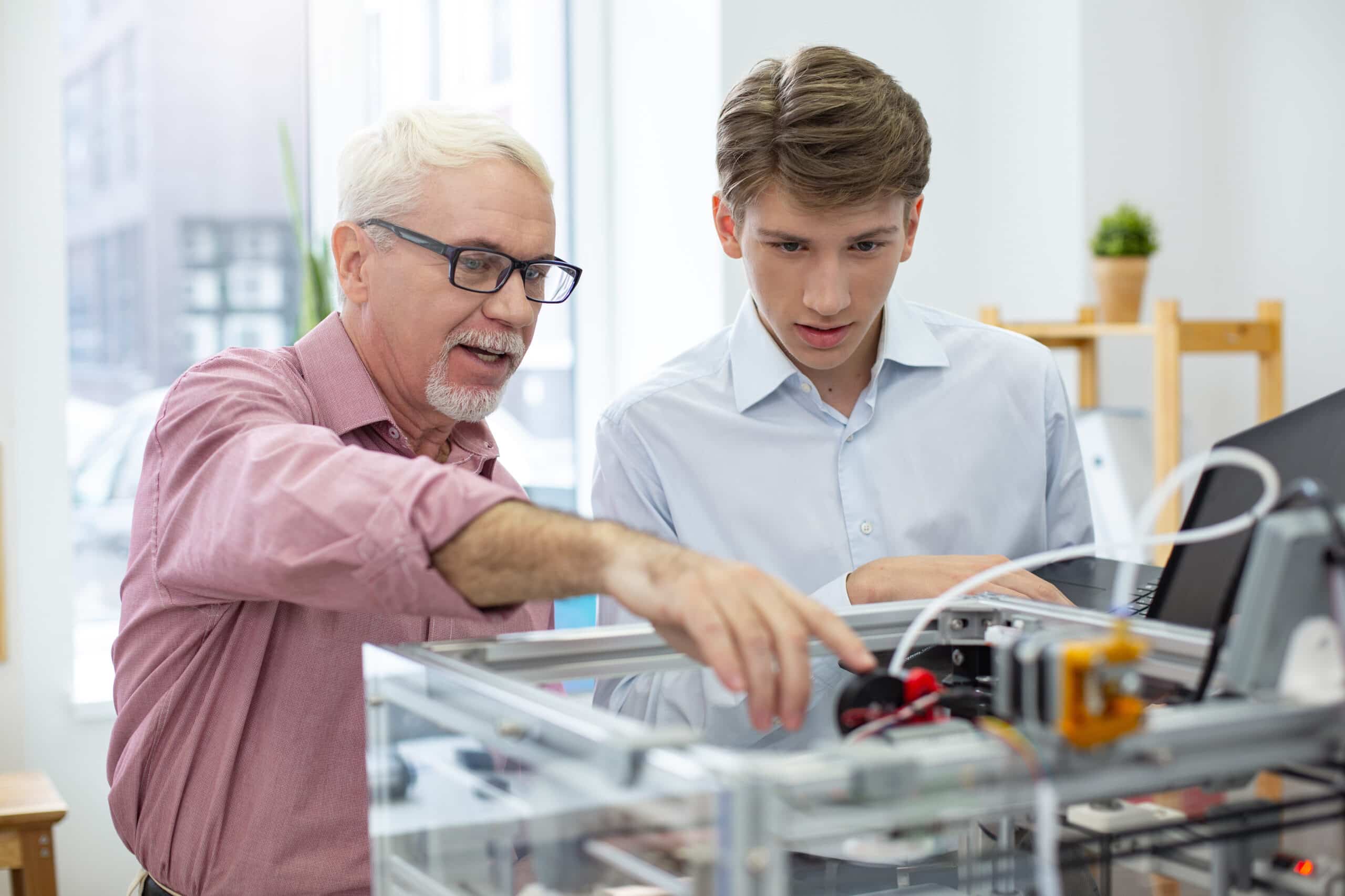 experienced senior engineer instructing intern about 3d printers