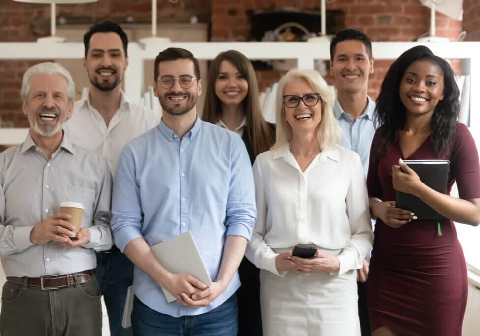 happy diverse business team standing in office looking at camera