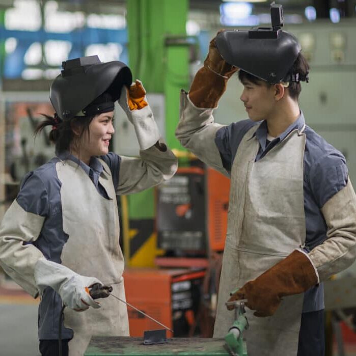 man and woman welding in factory.